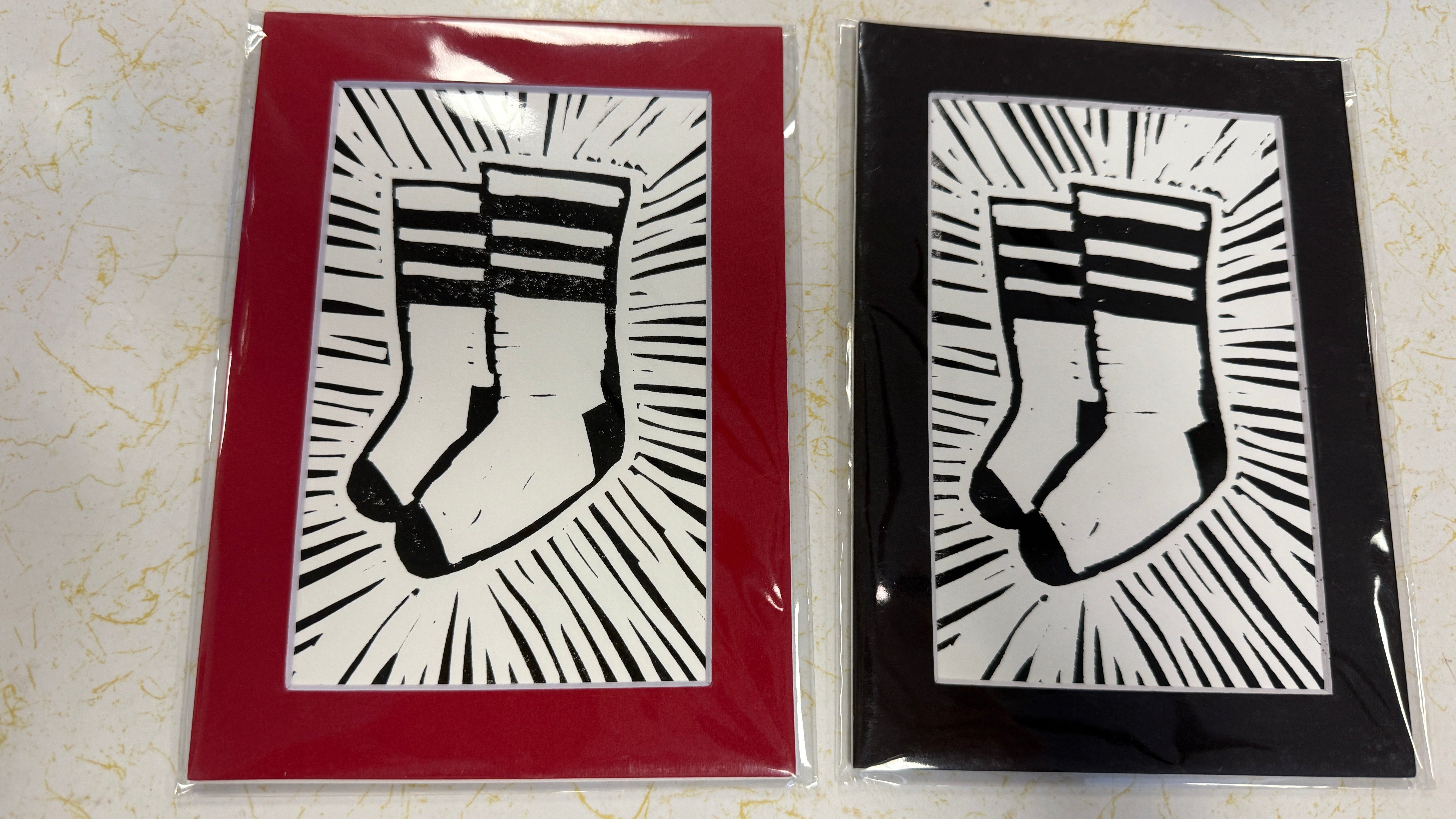 Two matted art prints featuring a black and white linocut-style raised fist graphic with radiating lines, shown side by side